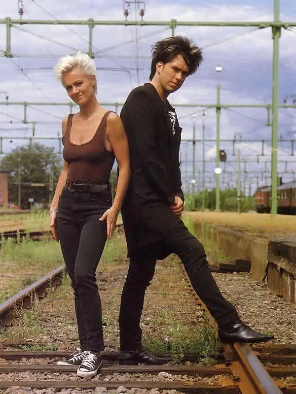 A promotional image for Roxette. Marie and Per are posing on a railroad track.